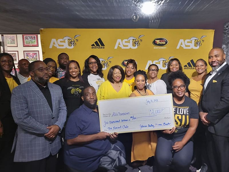 A group of people holding up a large check.